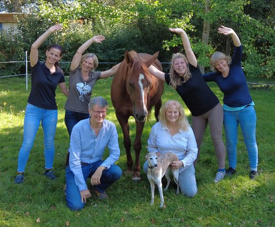 Horsemanship-Academy-Trainer. Sechs Menschen um ein Pferd herum und ein Hund in der Mitte.